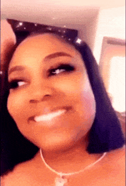a woman wearing a necklace and sunglasses is smiling .