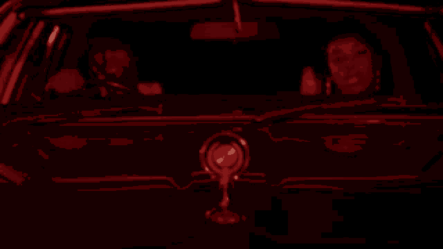 a man and a woman are sitting in a car that is lit up in red