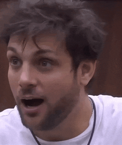 a man with a beard and a white shirt is making a surprised face