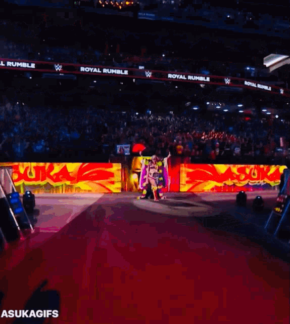 a group of people are walking on a stage with a sign that says royal rumble in the background