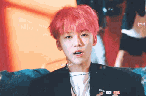 a man with pink hair is sitting on a couch