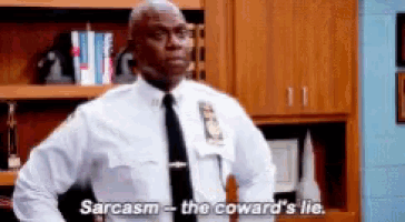 a police officer is standing in a room and saying sarcasm - the coward 's lie .