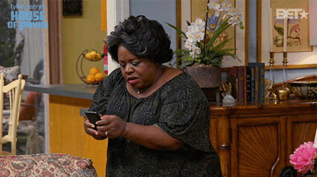 a woman is looking at her phone in a living room with a bet logo on the wall