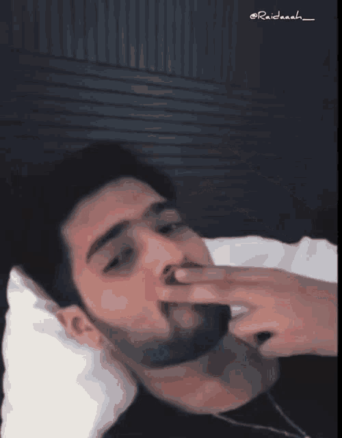 a man laying in bed with his hand on his nose