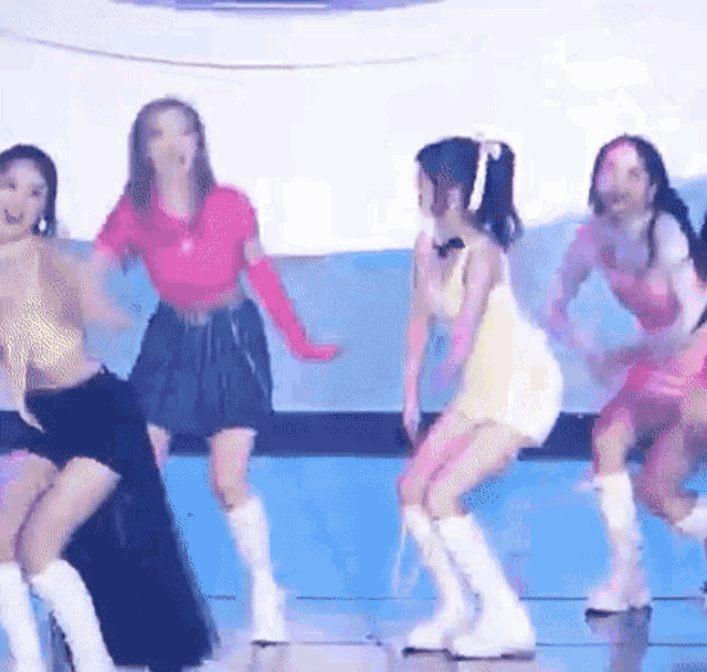 a group of young women are dancing on a stage in front of a crowd .