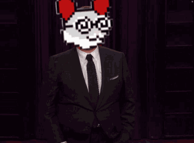 a man in a suit and tie is giving a peace sign with a pixelated face behind him