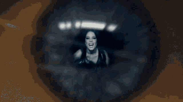 a woman with long hair is screaming in a dark room in a blurry photo .