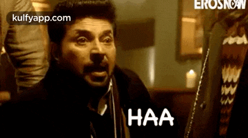 a man with a beard is talking on a cell phone and saying haa .