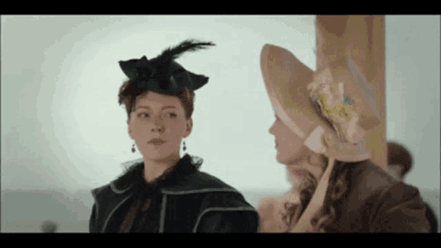 two women are standing next to each other wearing hats and looking at each other