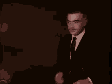 a man in a suit and tie is dancing in a dark room .