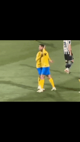 a soccer player wearing a yellow shirt and blue shorts is walking on the field