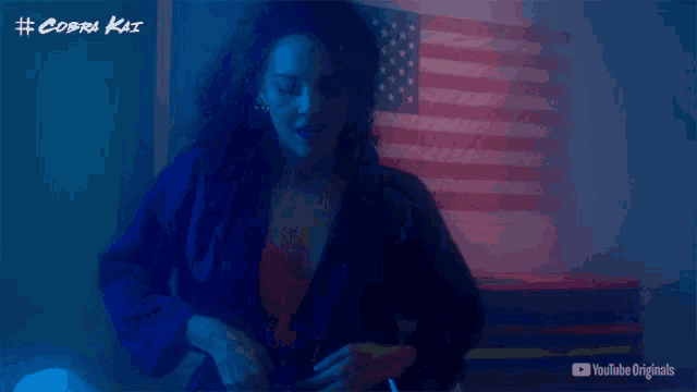 a person is standing in front of an american flag with # cobra kai written on the wall