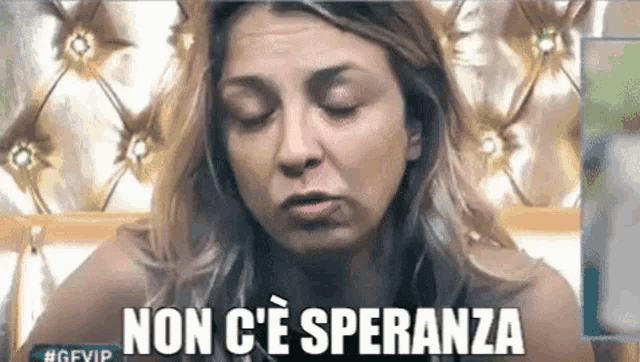 a woman with her eyes closed is sitting on a bed with the words non c ' e speranza written on the bottom .