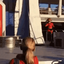 a woman in a ponytail is looking at a man in a red costume on a stage .