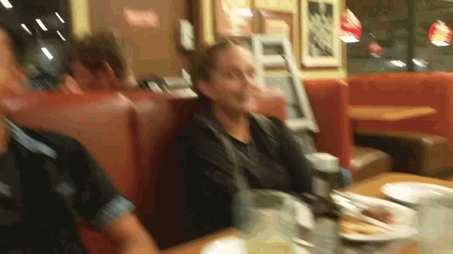 a group of people are sitting at a table in a diner