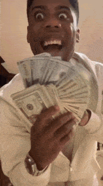 a man is holding a stack of 100 dollar bills in his hands