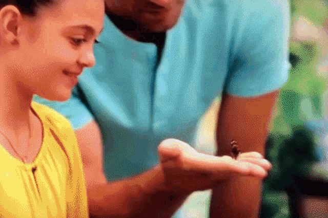 a man and a girl are looking at a butterfly on a person 's hand