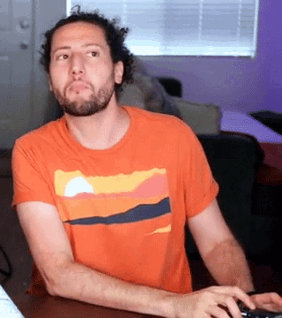 a man with a beard is wearing an orange shirt