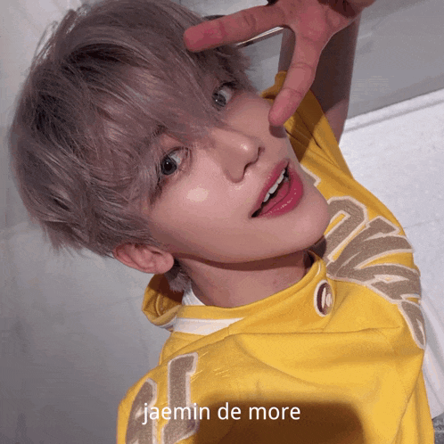 a young man wearing a yellow shirt with the name jaemin de more on the bottom