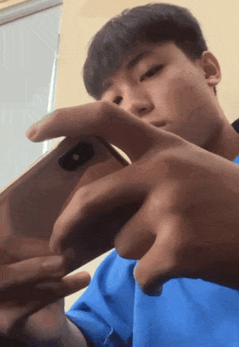 a man in a blue shirt is holding a cell phone