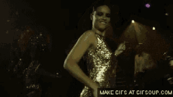 a woman in a gold dress is dancing in a dark room with the words make gifs at gifsoup.com below her