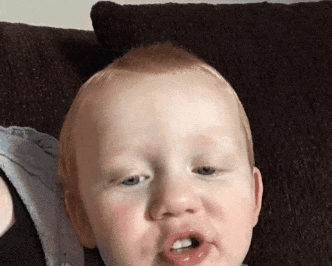 a close up of a baby making a funny face with his mouth open