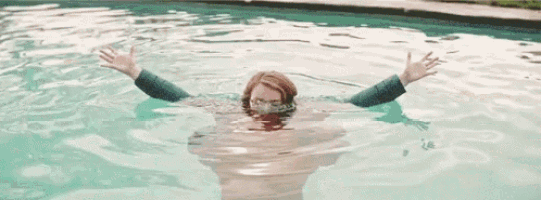 a woman is swimming in a pool with her arms outstretched .