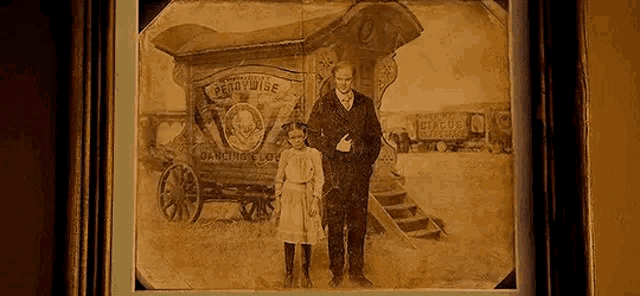 a man and a girl are standing next to each other in front of a wagon .
