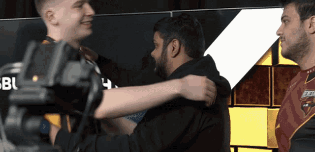 two men are hugging each other in front of a sign that says bbc