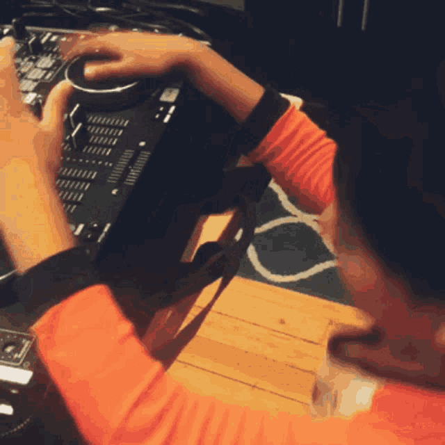 a person in an orange shirt is using a mixer on a table