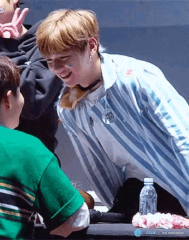 a man in a blue and white striped shirt is talking to another man