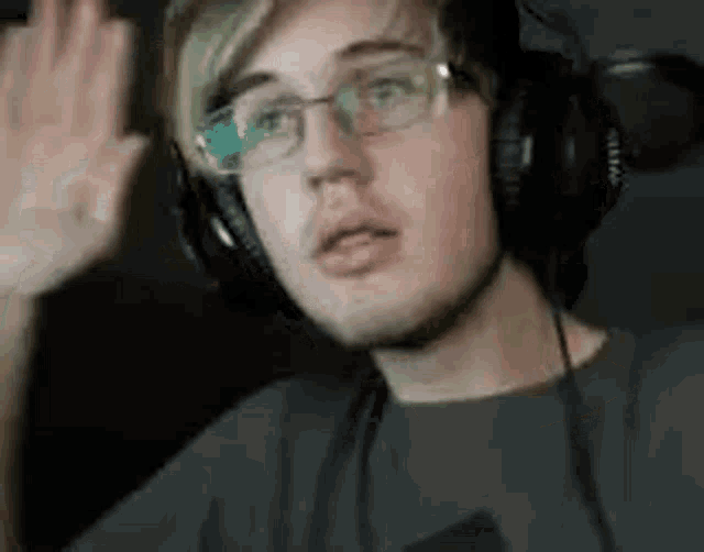 a young man wearing headphones and glasses is making a funny face .