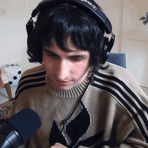 a man wearing headphones and a adidas sweater