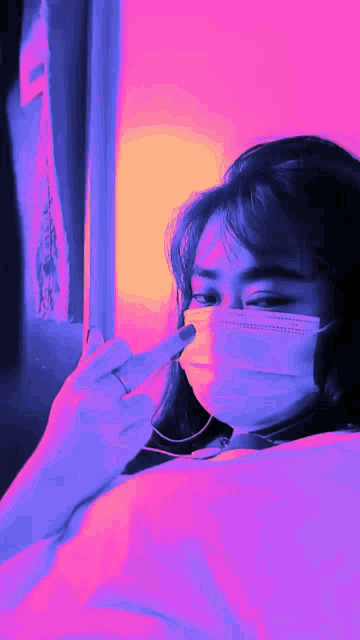 a woman wearing a face mask and a ring is giving the middle finger
