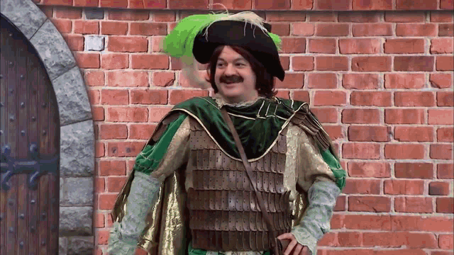 a man in a green and gold costume is standing in front of a red brick wall