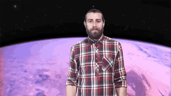 a man with a beard wearing a plaid shirt stands in front of a planet