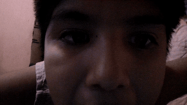 a close up of a person 's face with a pink wall behind them