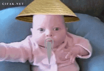 a baby wearing a straw hat with a long mustache is sitting on a blue pillow ..