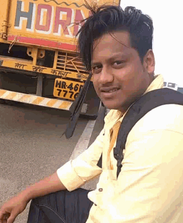 a man is sitting in front of a yellow truck that says horn