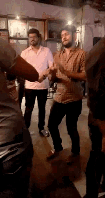 a group of men are dancing together in a room while holding hands .