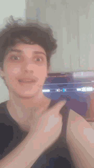 a man in a black tank top is pointing at something in front of a television