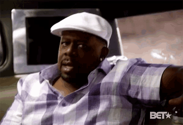 a man wearing a white hat and a plaid shirt is sitting in a car with the bet logo on the bottom