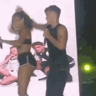 a man is holding a microphone while a woman dances on stage .