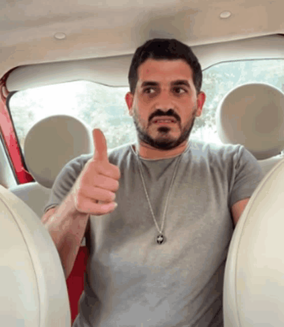 a man in a car giving a thumbs up sign