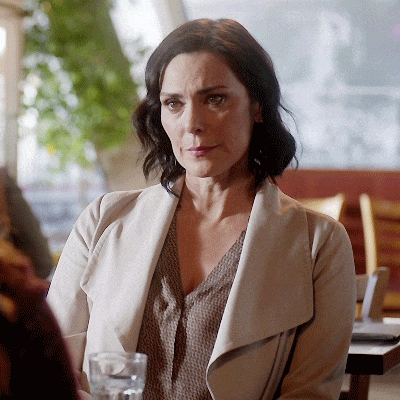 a woman sitting at a table with a glass of water in her hand