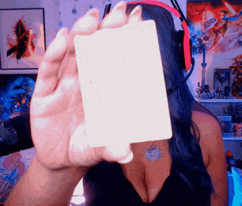 a woman wearing headphones is holding a card in front of her face