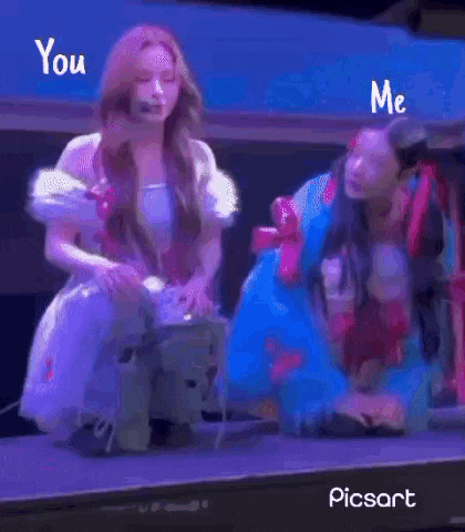 two women are standing next to each other on a stage and one of them is kneeling down .