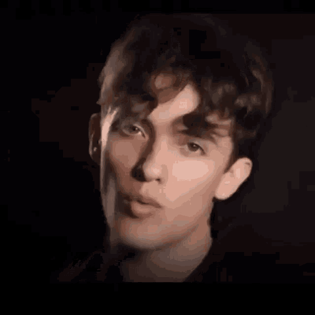 a young man with curly hair is singing into a microphone .