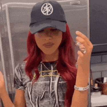 a woman with red hair is wearing a hat and holding a ring .