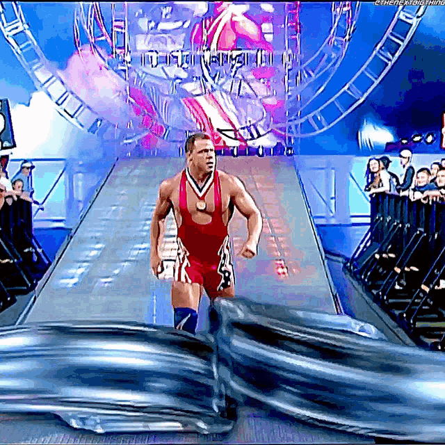 a wrestler with a medal around his neck is walking down a runway